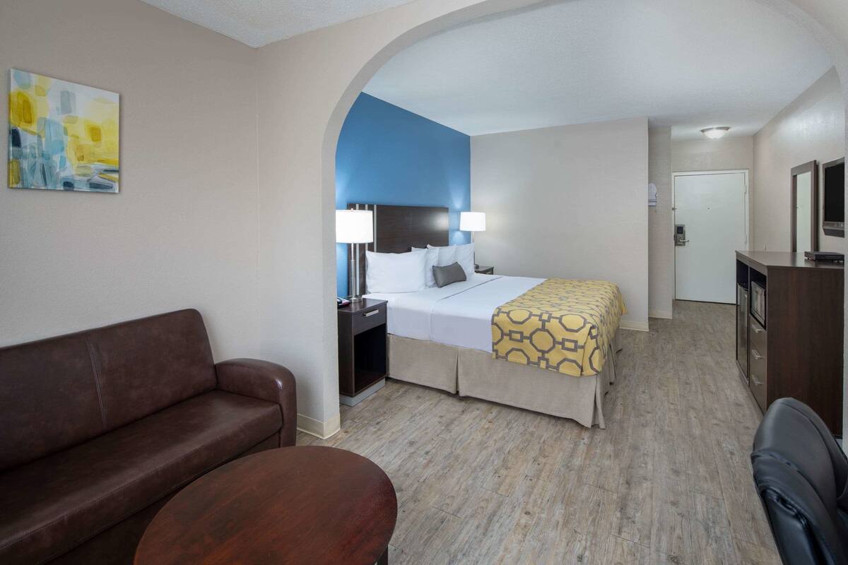 A hotel room with a bed, a sofa, a desk, and a television.