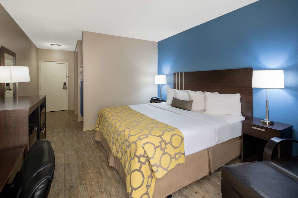 A hotel room with a bed, bedside lamps, a desk, and a chair.