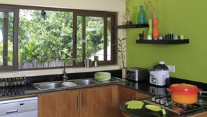 A kitchen with a dishwasher, sink, stove, and a window overlooking greenery. - Villa Fayette Sur Mer (Poste Lafayette)