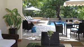 A poolside area with lounge chairs, a dining table, and a potted plant. - Villa Fayette Sur Mer (Poste Lafayette)