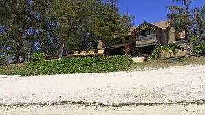 A beachfront property with a large house, clear shallow waters, and lush greenery. - Villa Fayette Sur Mer (Poste Lafayette)