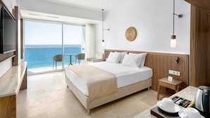 Una habitación de hotel moderna con una cama grande, un escritorio, una silla y vista al mar.