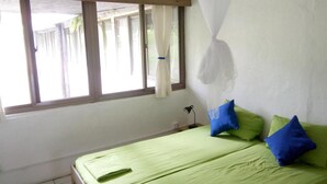 A room with a bed, a window with curtains, and a mosquito net. - Richmond Vale Diving and Hiking Center - Hostel (Chateaubelair)