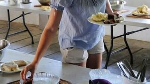 A person serving food at a table in a room with large windows and a simple, functional design. - Richmond Vale Diving and Hiking Center - Hostel (Chateaubelair)