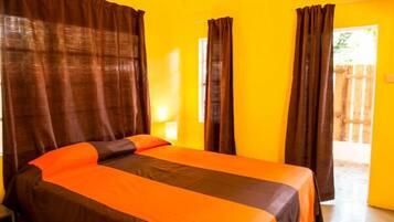 A room with two beds, each with an orange bedspread and brown curtains.
