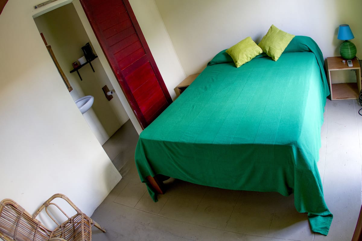 A room with a bed, a nightstand, a lamp, and a door.