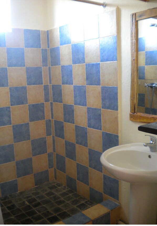 A bathroom with checkered blue and beige tiles, a white sink, and a wooden-framed mirror.