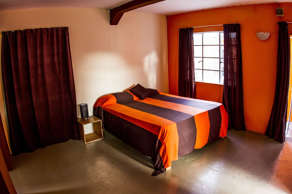 A room with a bed, a window, and curtains.