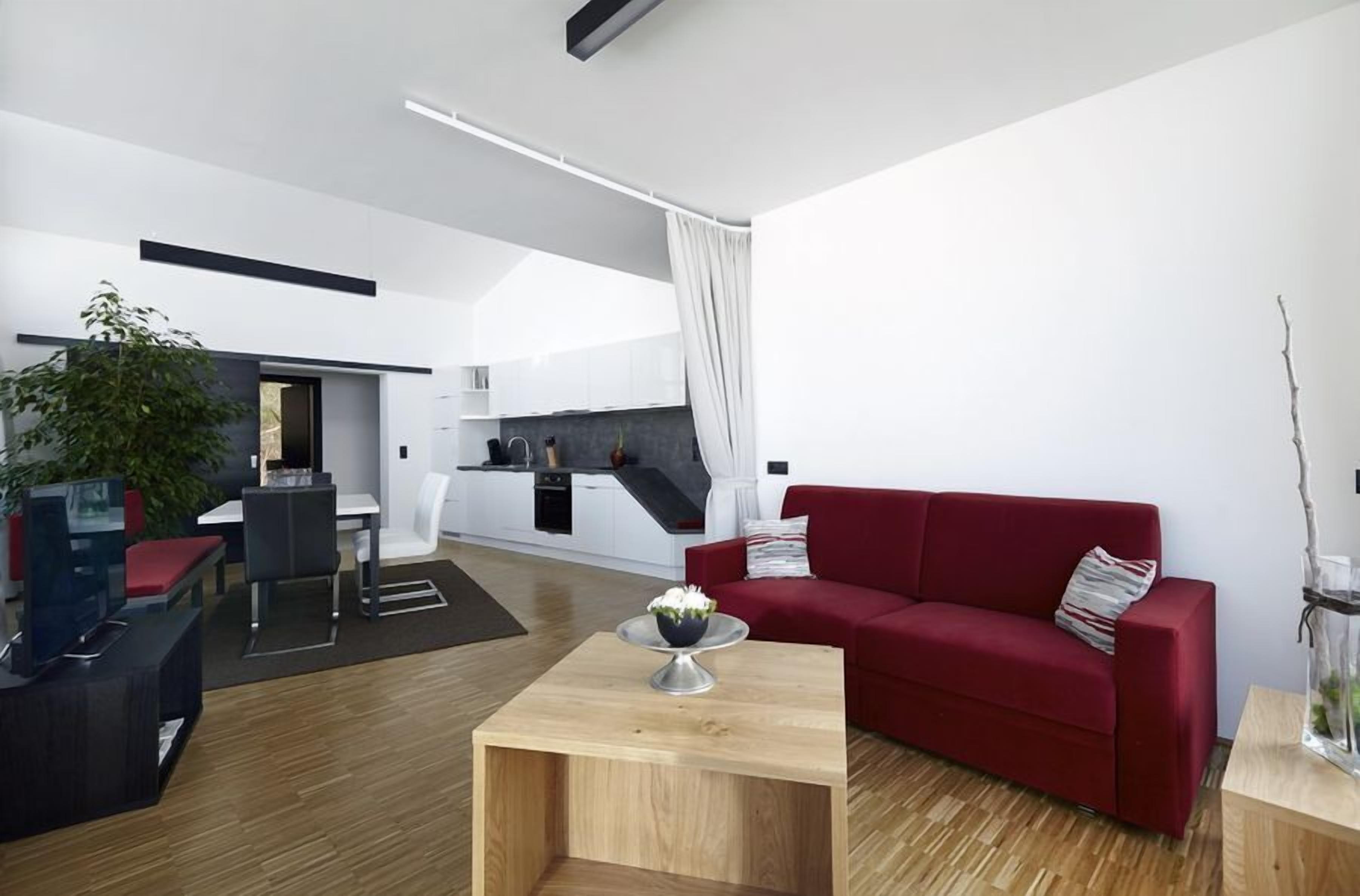 Una sala de estar moderna con un sofá rojo, una mesa de centro de madera y un mueble para televisión.