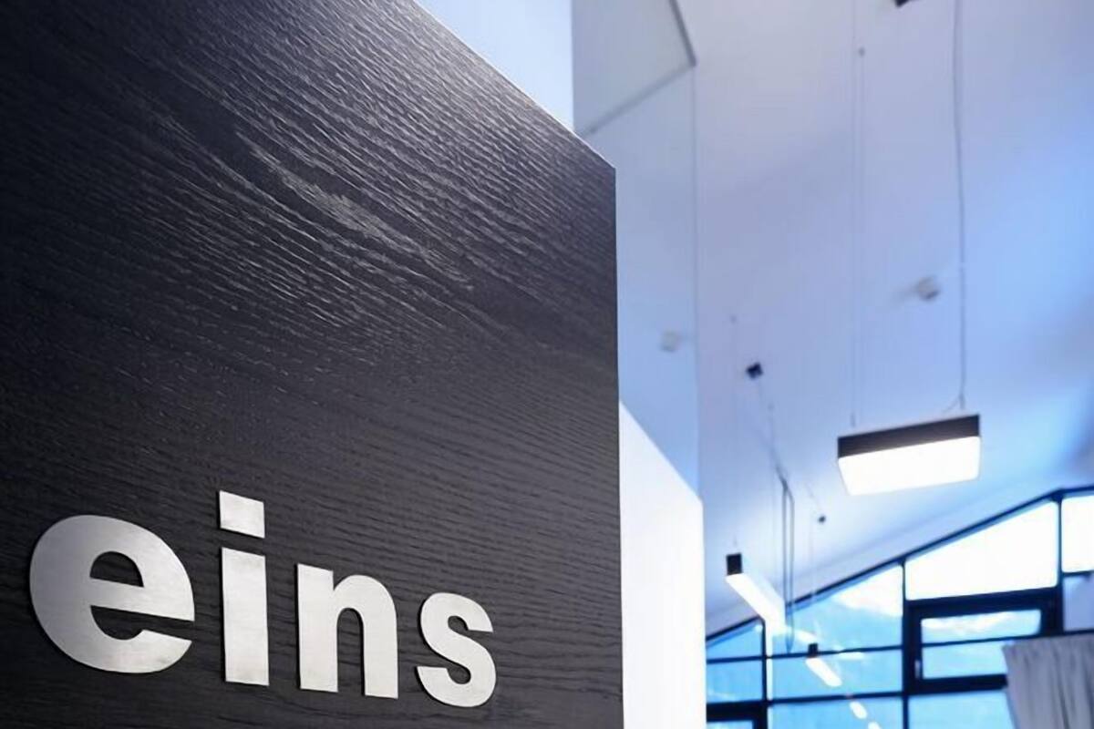 A modern office interior with a black door labeled "eins".