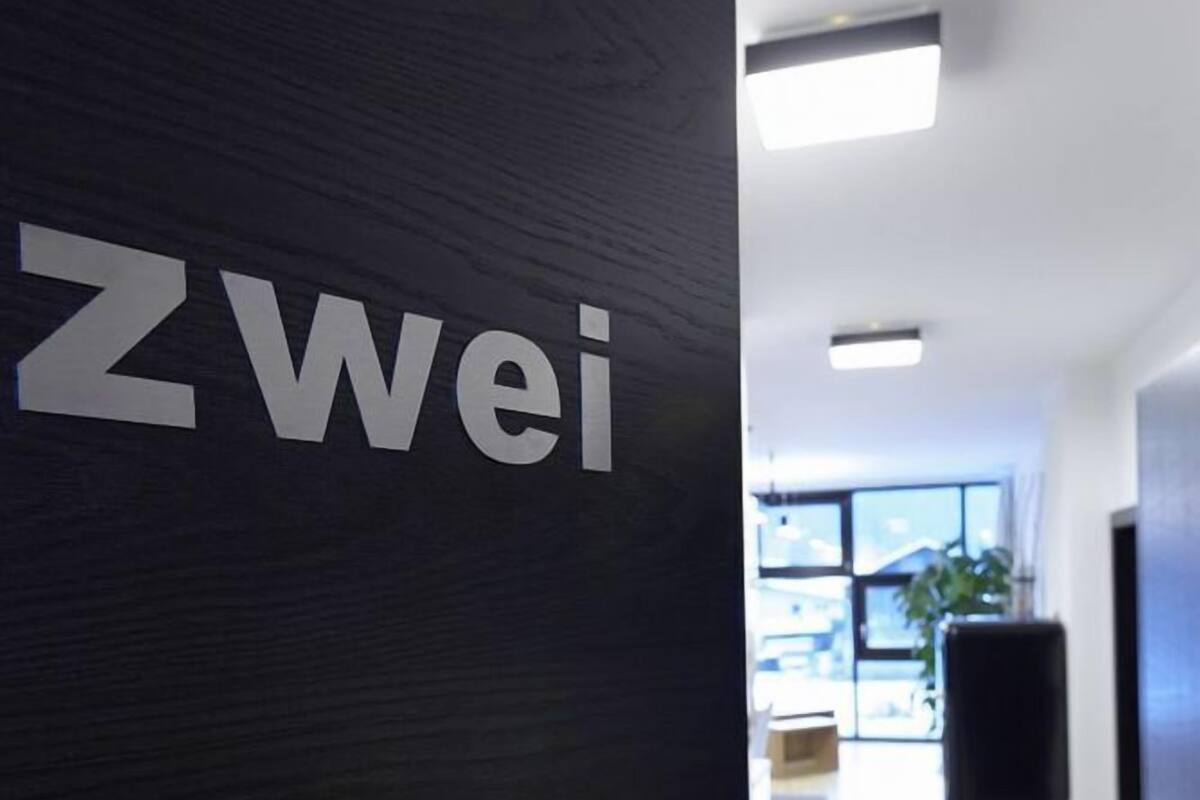 A modern interior with a dark wooden door labeled "Zwei".