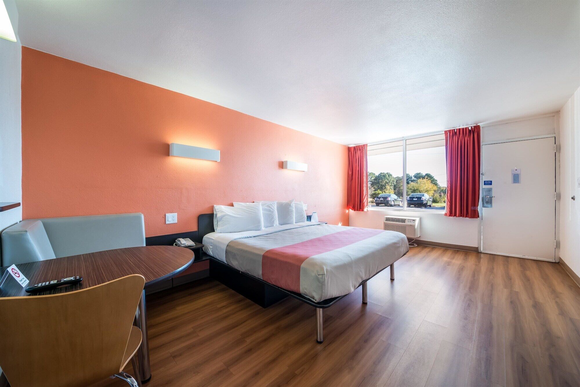 Habitación de hotel con cama, escritorio, silla y ventana con cortinas.