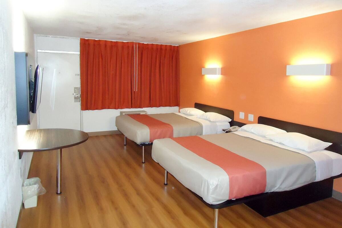 A hotel room with two beds, a small table, and a TV.