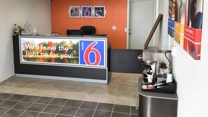A hotel reception area with a counter displaying a sign for 'Motel 6' and a message about leaving the light on for guests. - Motel 6 Connellys Springs, NC (Icard)