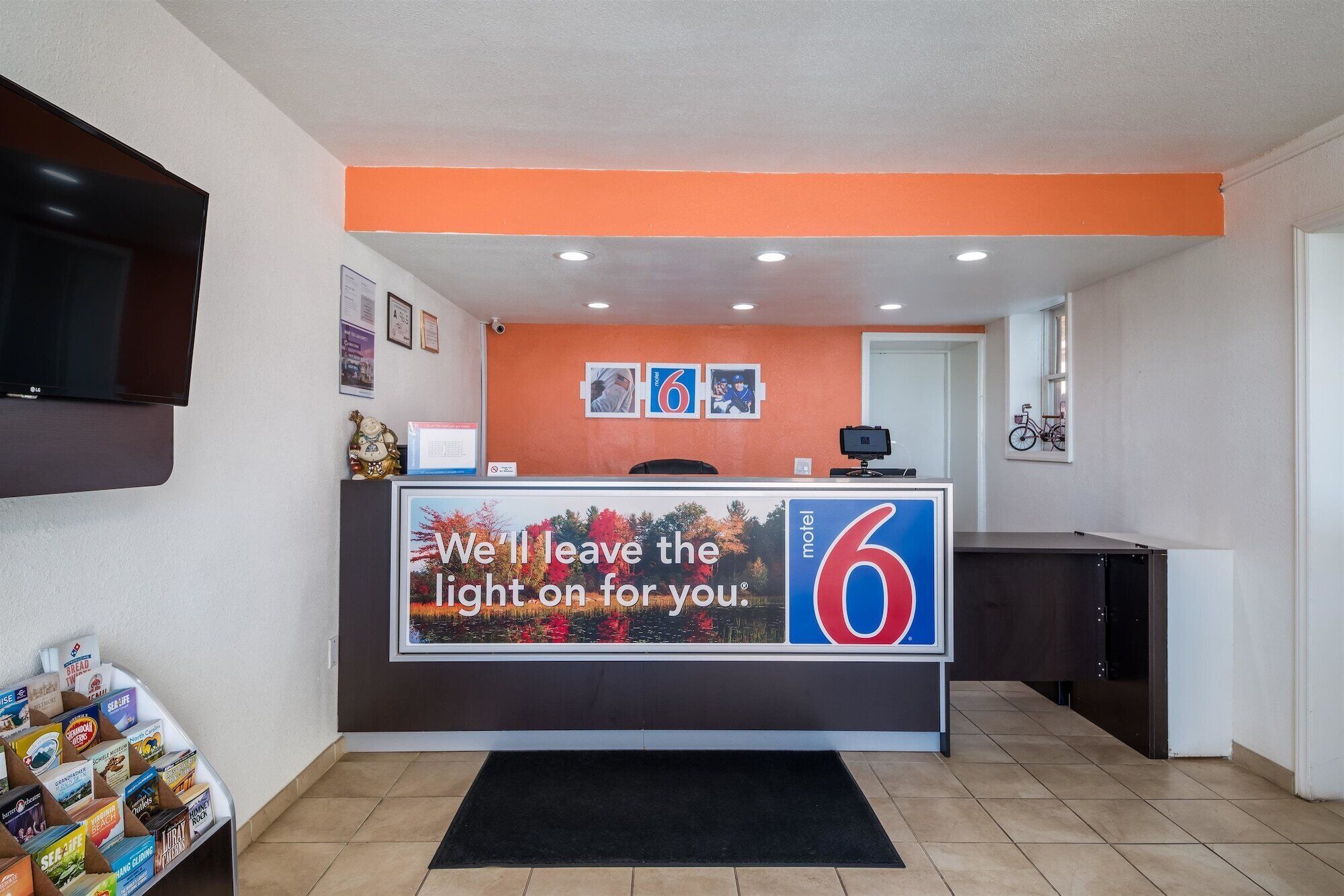 A motel reception desk with a large sign reading "We'll leave the light on for you."