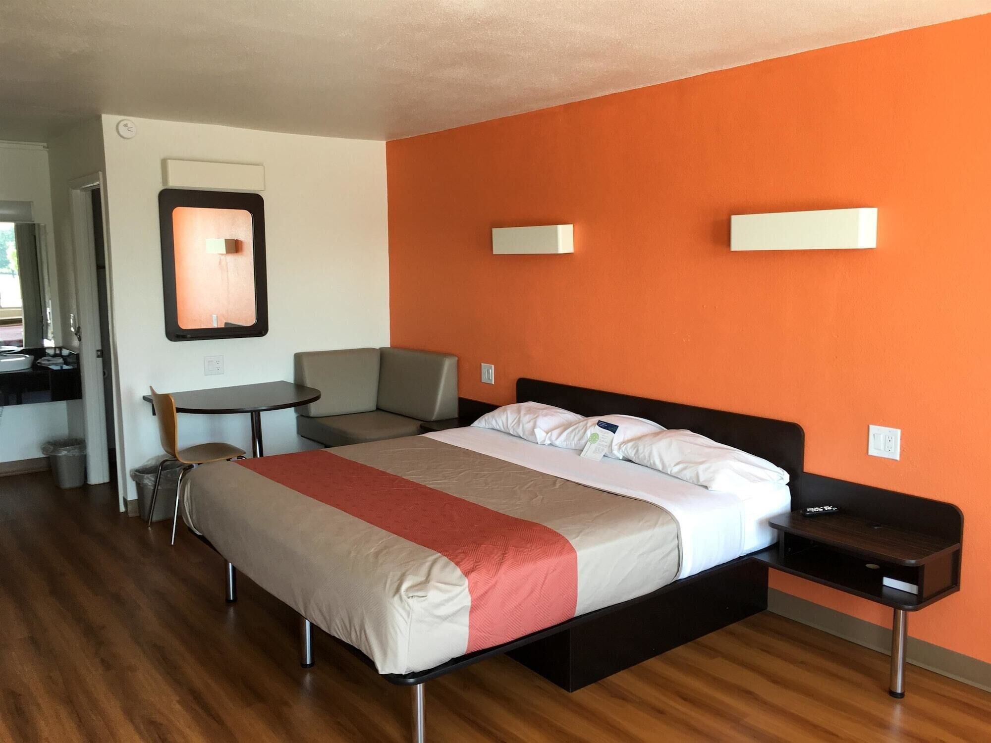 A hotel room with a bed, a desk, a chair, and a small table.