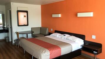 A hotel room with a bed, a desk, a chair, and a small table.