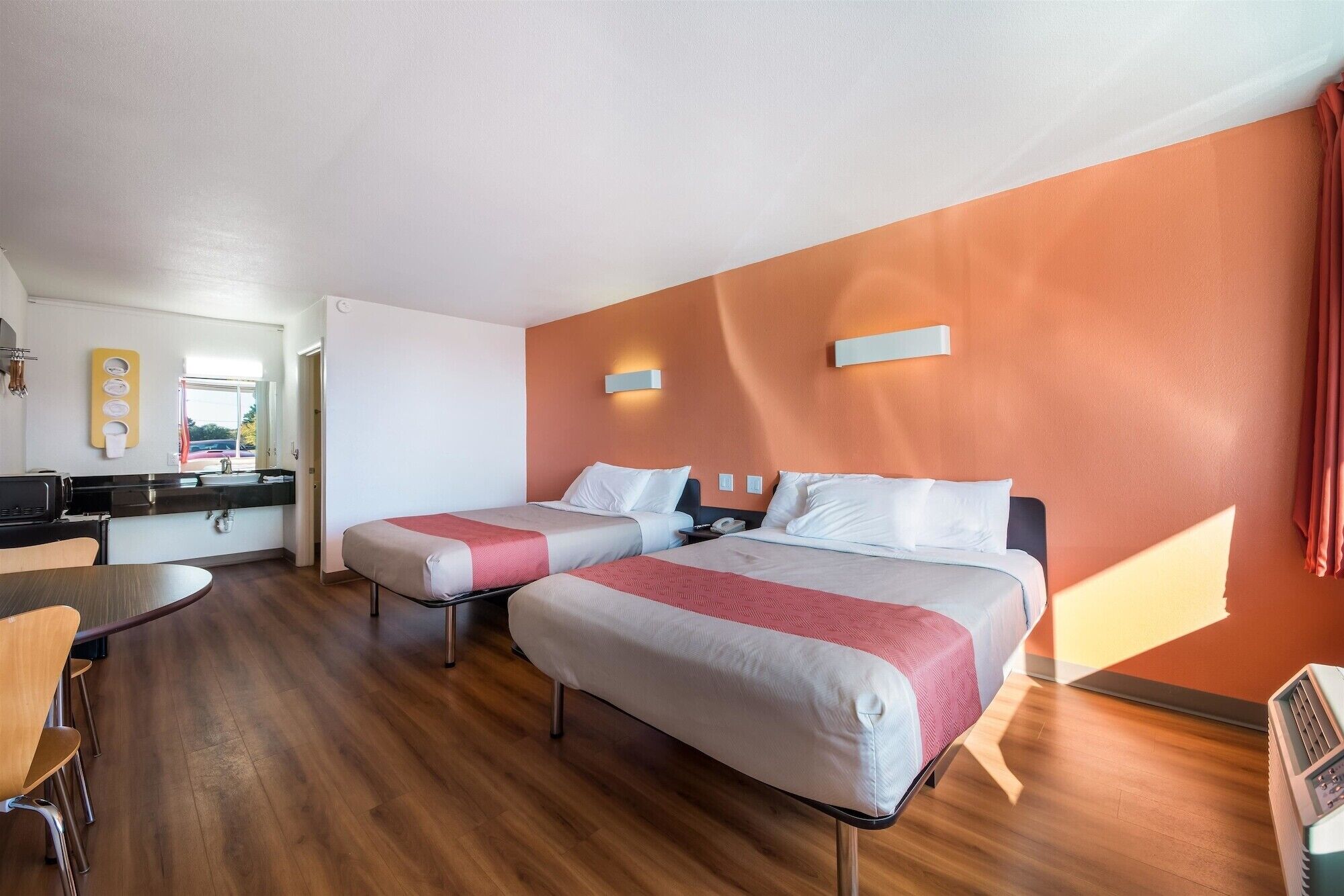 Ein Hotelzimmer mit zwei Betten, einer Küchenzeile und einem Essbereich.