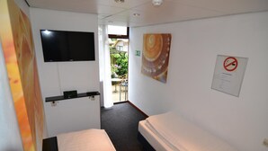 A hotel room with a bed, a TV, a small shelf, and a view of the outside. - Hotel Bienvenue (Rotterdam)