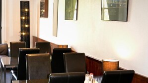 A restaurant with booths and tables, a clock on the wall, and framed pictures. - Hotel Bienvenue (Rotterdam)