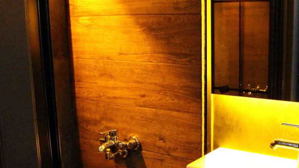 A bathroom with a wooden floor, a white sink, and a towel rack. - İstanbul Fair Hotel (Istanbul)
