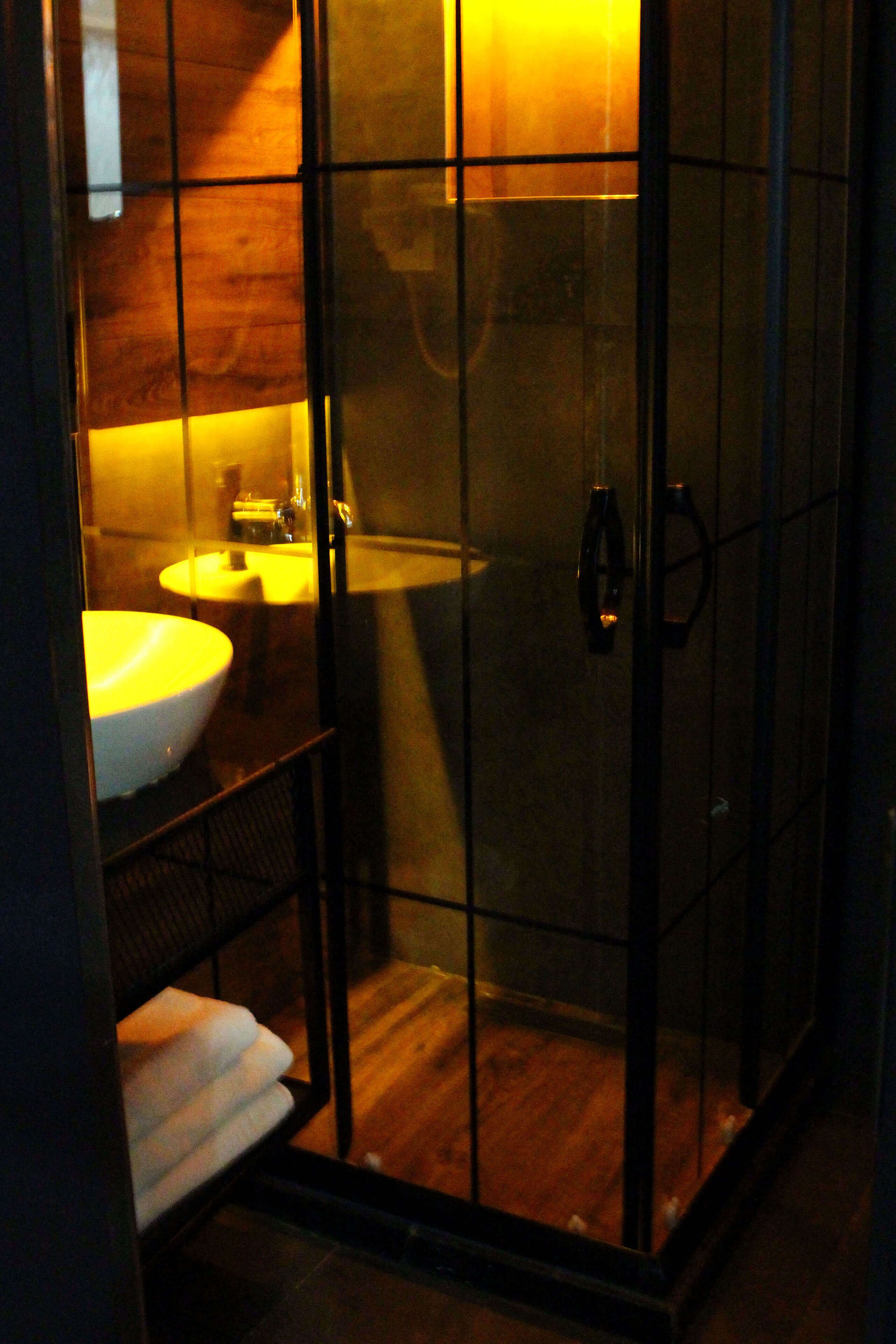A bathroom with a glass-enclosed shower, a sink, and a mirror.