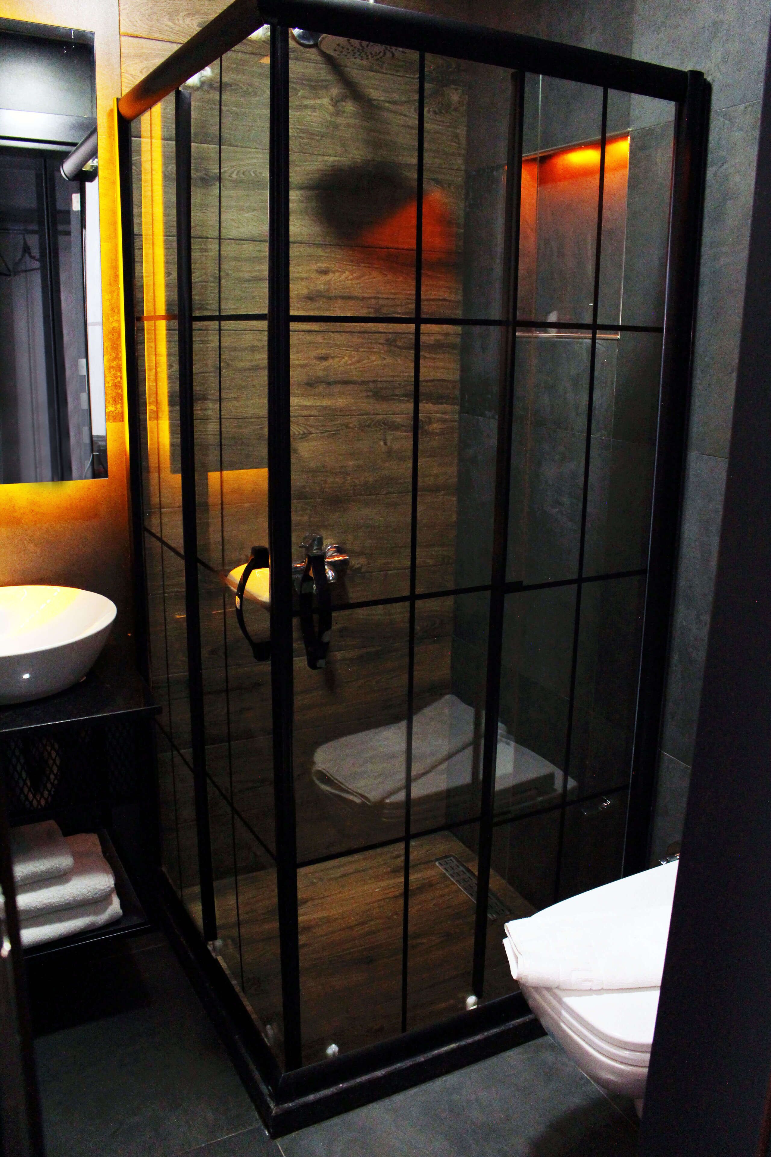 Un bany modern amb dutxa envidrada, un lavabo blanc i un mirall.