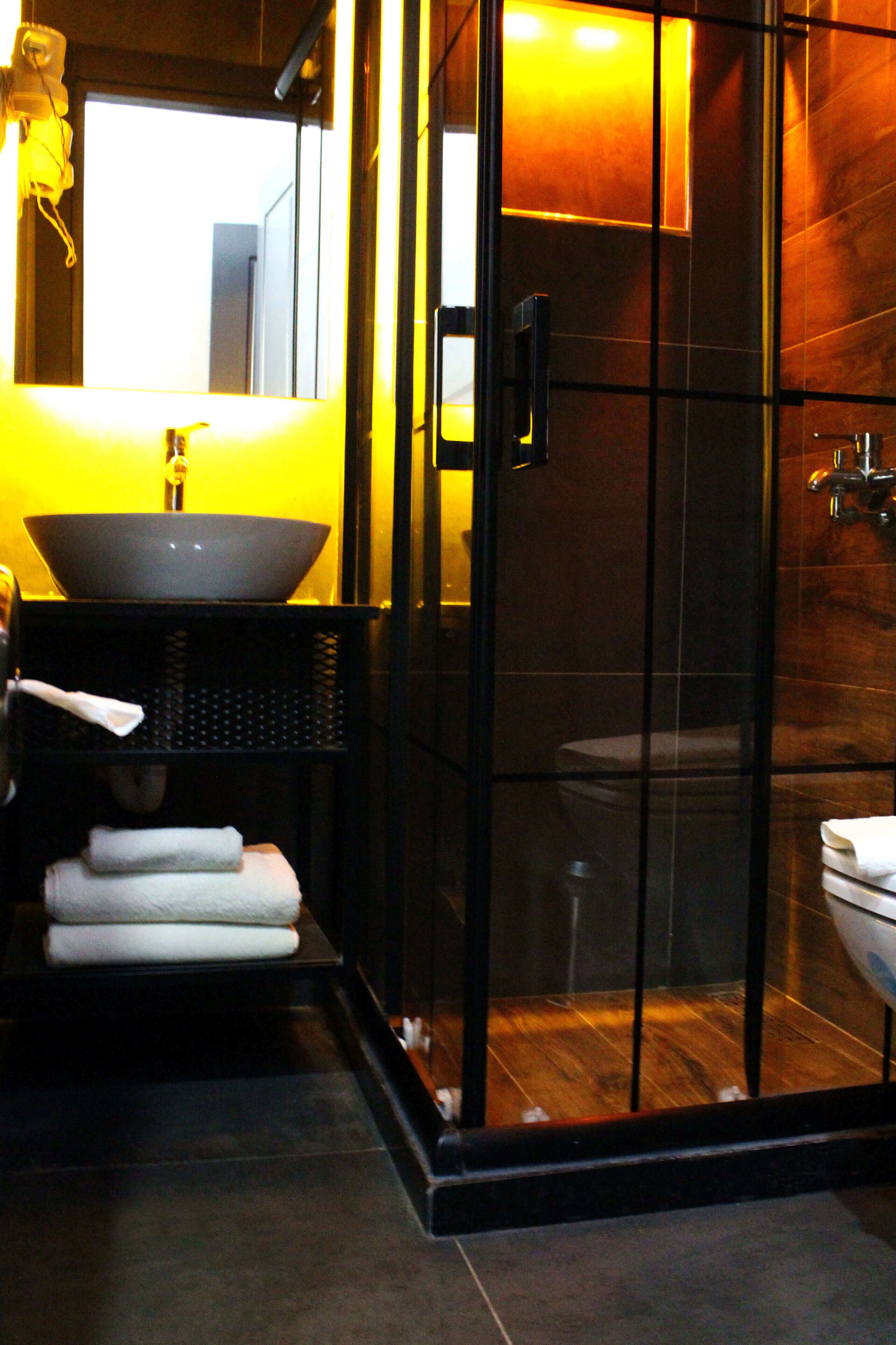 Un baño moderno con ducha envuelta en vidrio, un lavabo negro y un inodoro blanco.