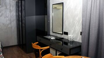 Una habitación de hotel moderna con una mesa de comedor de madera, un escritorio negro con un espejo y una silla.