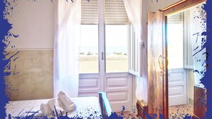 Una habitación de hotel con una cama, una puerta de baño y vista a la playa.