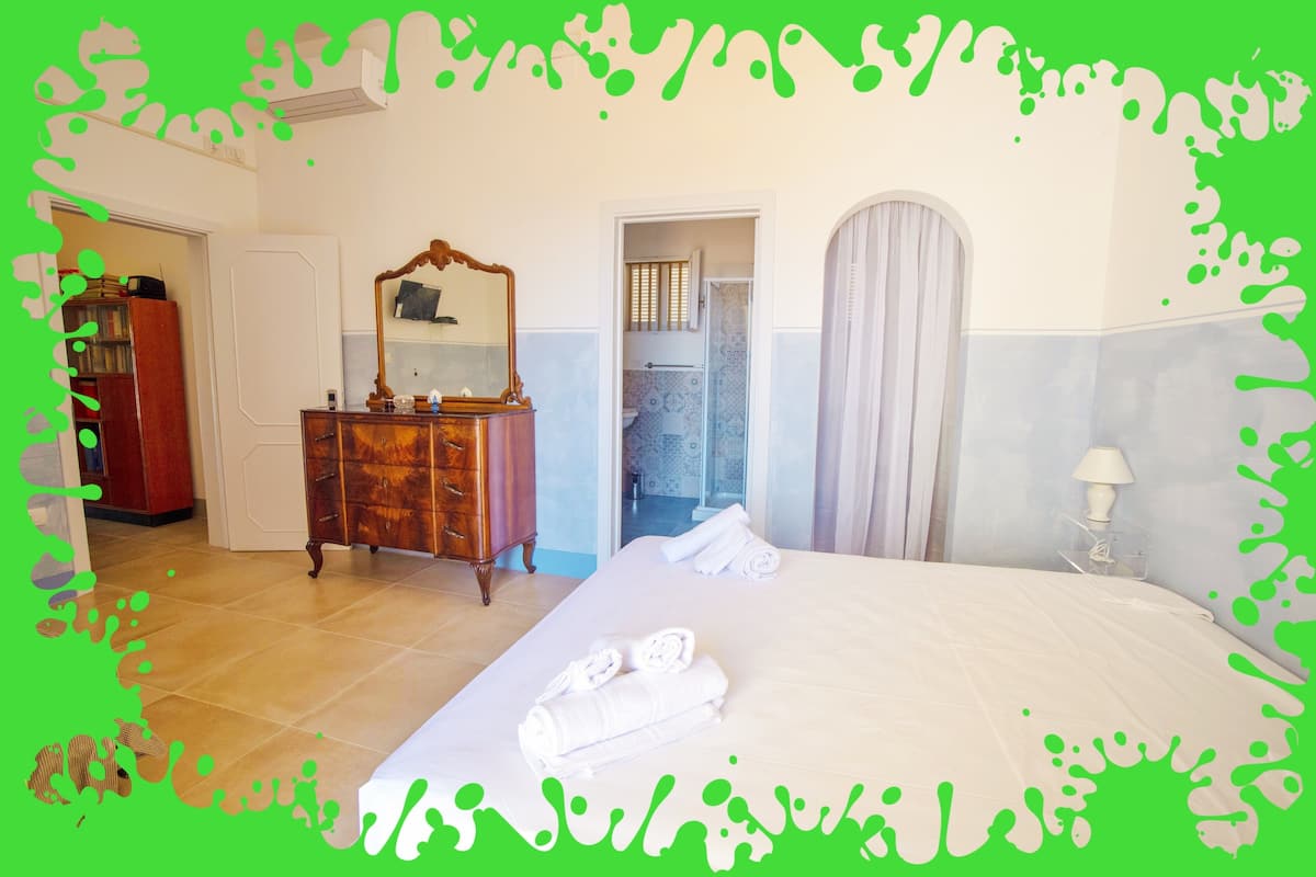 A hotel room with a bed, a dresser, a mirror, and a bathroom door.