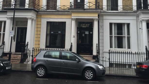 Une rangée de maisons mitoyennes avec une voiture grise garée devant.