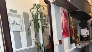 Un couloir avec un grand miroir, une plante en pot et un téléphone public.