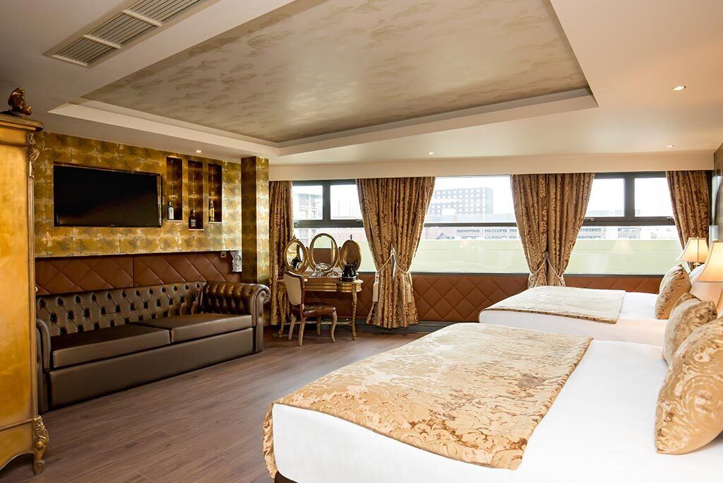Une chambre d’hôtel avec un grand lit, un canapé, un bureau avec un miroir et une télévision.