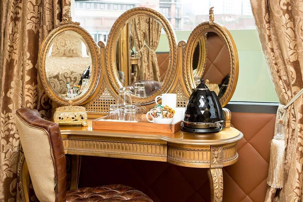 A luxurious vanity with ornate mirrors, a vanity table, and a plush chair.