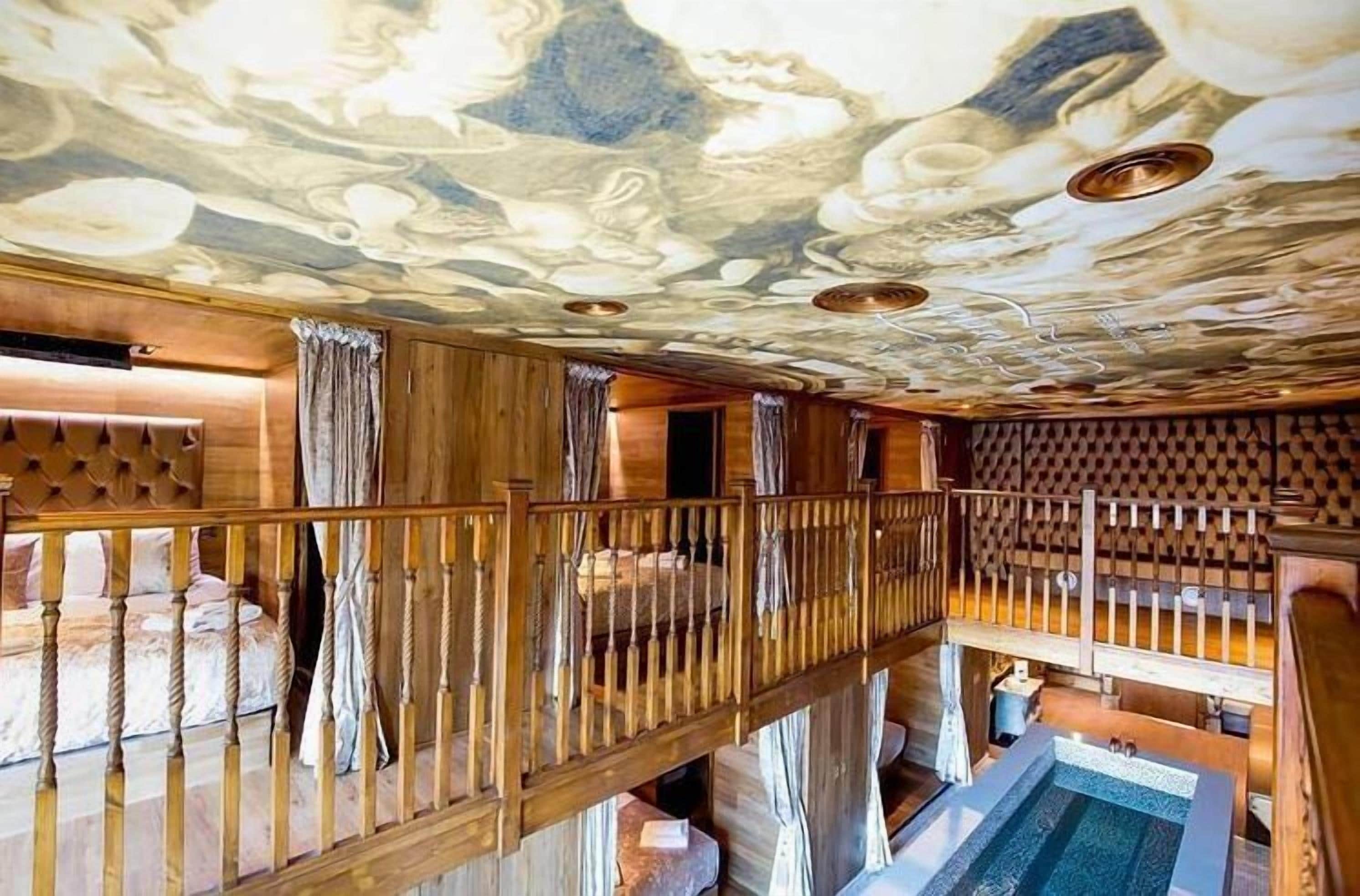 Interior de madeira em vários níveis, com piscina, corrimãos de madeira e teto com design semelhante ao mármore.