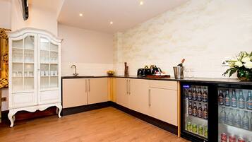 A modern kitchen with wooden cabinets, a built-in refrigerator stocked with beverages, and a decorative cabinet with glassware.