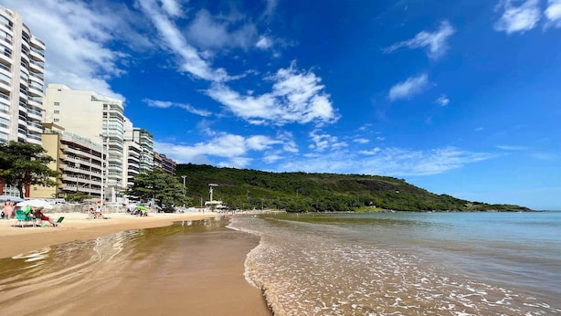 A beach with a sandy shore, a clear blue sky, and a forested hill in the background. - Guarapari Praia (Guarapari)