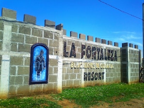 A sign for La Fortaleza De Granada Resort, featuring a stone wall with a mural of a knight and the resort's name.