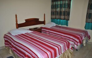 A double bed with a wooden headboard, a bedside table, and a striped bedspread.