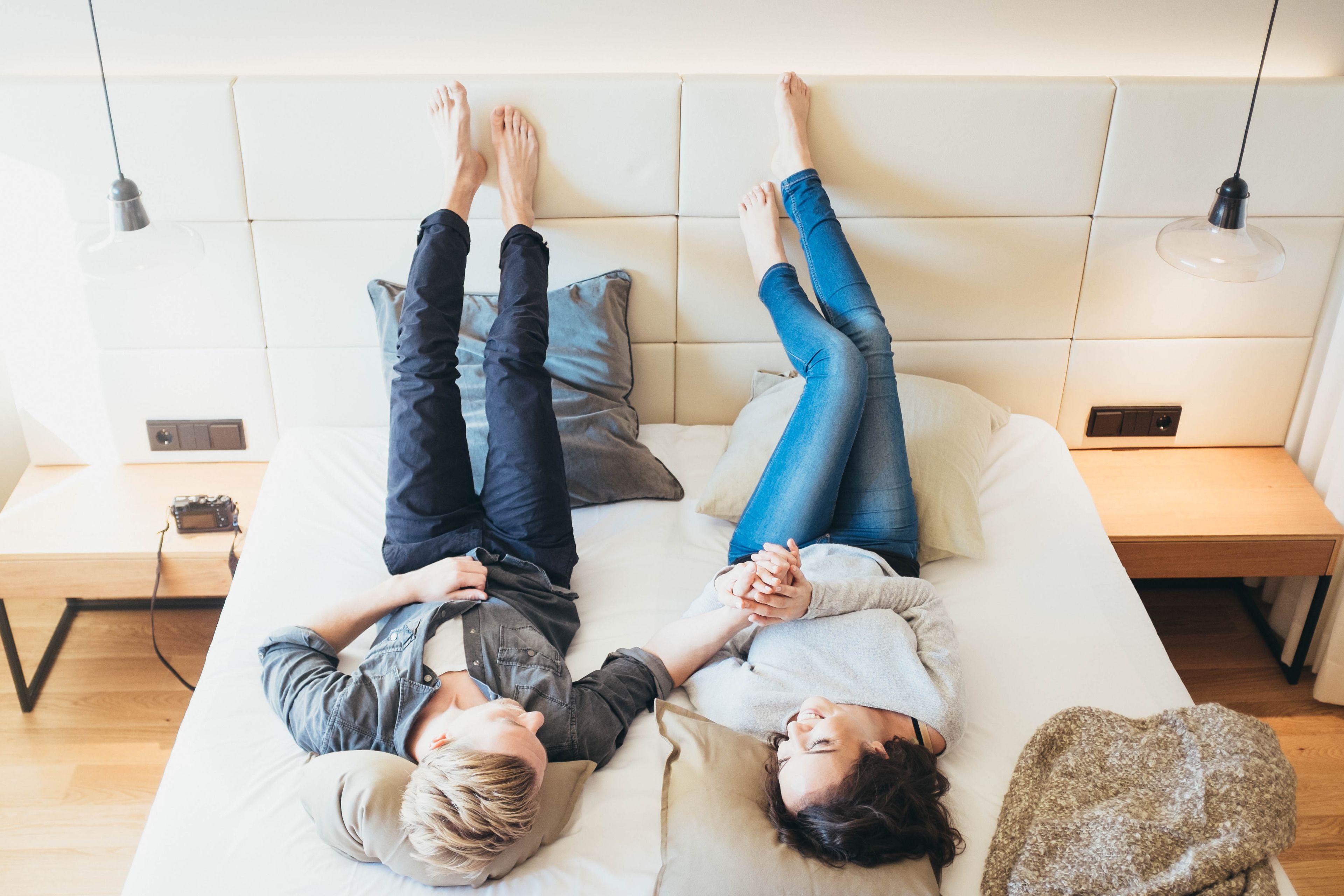 A bed with two people lying on it, a bedside table, and a lamp.