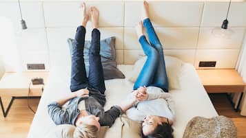 A bed with two people lying on it, a bedside table, and a lamp.