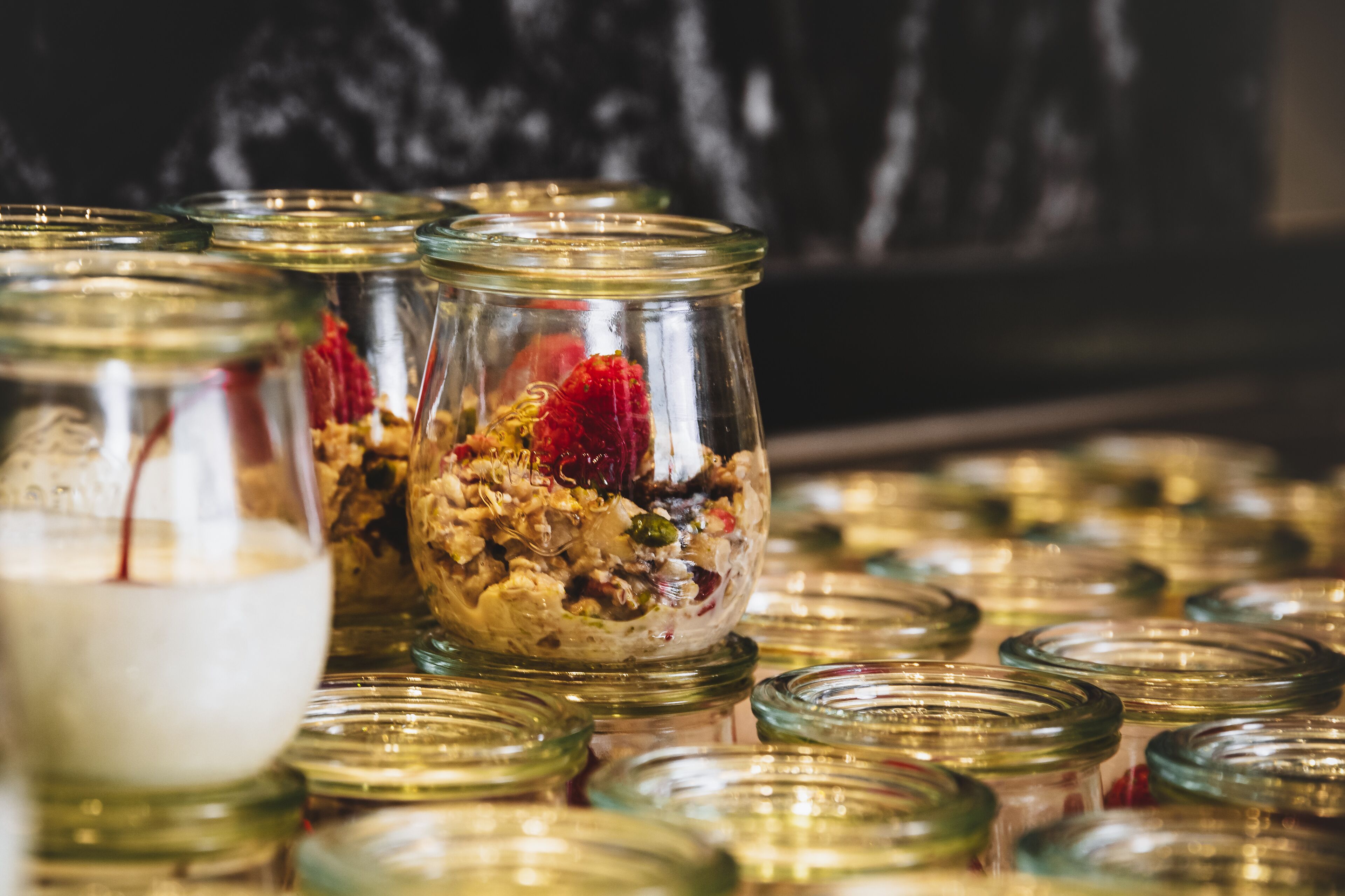 Varios frascos de vidrio con tapas, algunos conteniendo alimentos, dispuestos sobre una superficie.