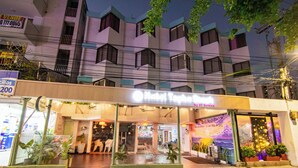 A hotel with a modern facade, large windows, and a visible entrance area with seating and potted plants. - Hotel Taybo Beach (Santa Marta)