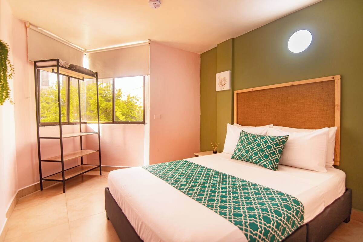 Une chambre à coucher avec un lit, une fenêtre, une étagère et un luminaire au plafond.