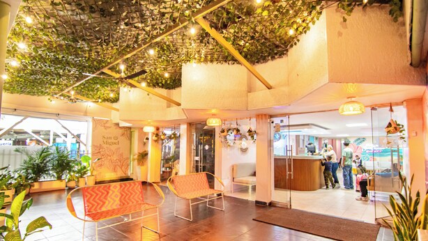 A lobby with a reception desk, seating area, and potted plants. - Hotel Taybo Beach (Santa Marta)