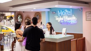 A hotel reception desk with a neon sign for 'Hotel Taybo Beach By ST Hotels'. - Hotel Taybo Beach (Santa Marta)