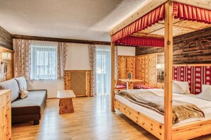 A wooden cabin-style room with a bed, sofa, and a small table. - Hotel Alpenstolz (Mieders)