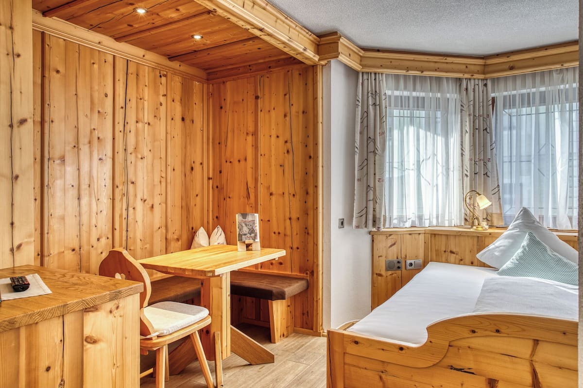 A wooden cabin room with a bed, a wooden table, and a bench.