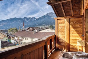 A wooden balcony with a view of a mountain and a church. - Hotel Alpenstolz (Mieders)